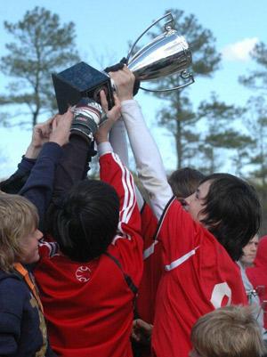 boys youth club soccer player hoist a soccer trophy